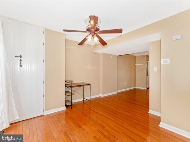 empty room featuring a ceiling fan, wood-type flooring, and baseboards