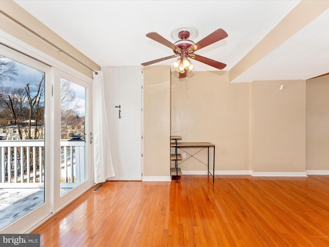 spare room with light wood-type flooring, visible vents, ceiling fan, and baseboards