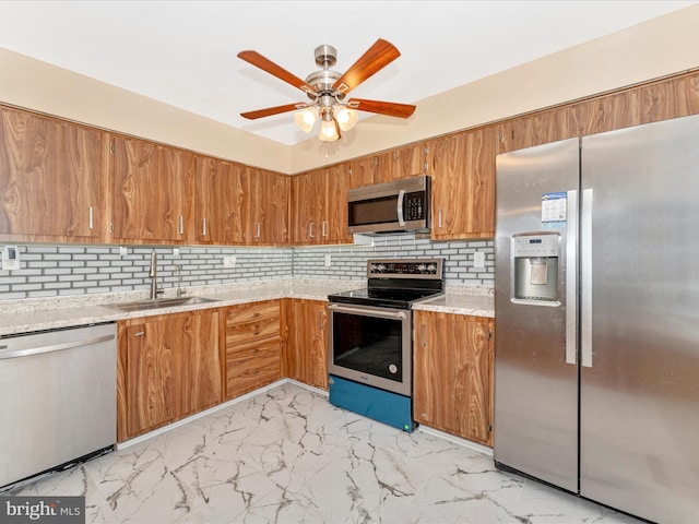 kitchen with stainless steel appliances, marble finish floor, brown cabinetry, and a sink