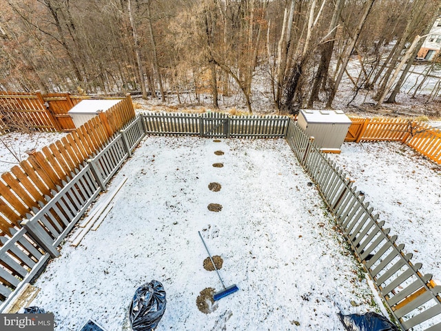 snowy yard featuring an outbuilding, a storage unit, and a fenced backyard