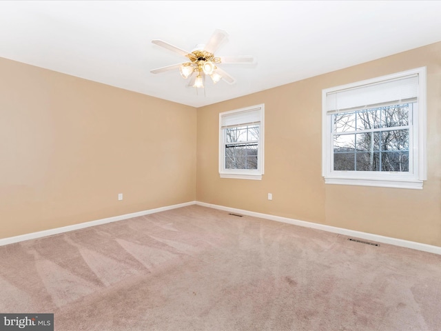 carpeted spare room with baseboards, visible vents, and a ceiling fan