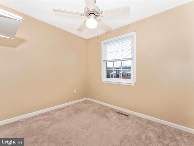 carpeted spare room with a ceiling fan, visible vents, and baseboards