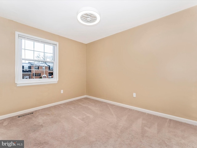 spare room featuring baseboards, visible vents, and light colored carpet