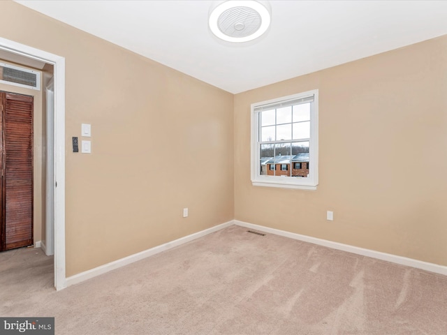 spare room featuring light carpet, visible vents, and baseboards