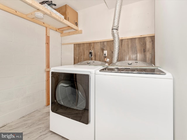 laundry area with concrete block wall, laundry area, wooden walls, and washer and dryer