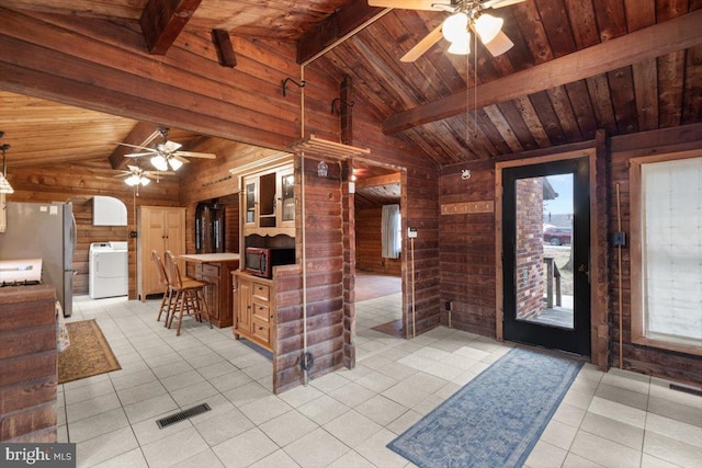 entryway featuring light tile patterned floors, wooden walls, lofted ceiling with beams, wooden ceiling, and washer / clothes dryer