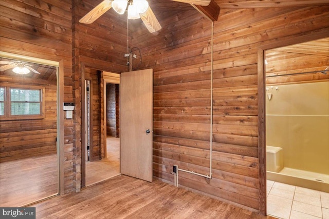 unfurnished bedroom with lofted ceiling, wood finished floors, and wooden walls