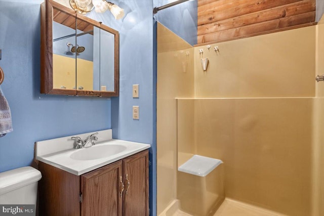 bathroom featuring toilet, a shower, and vanity