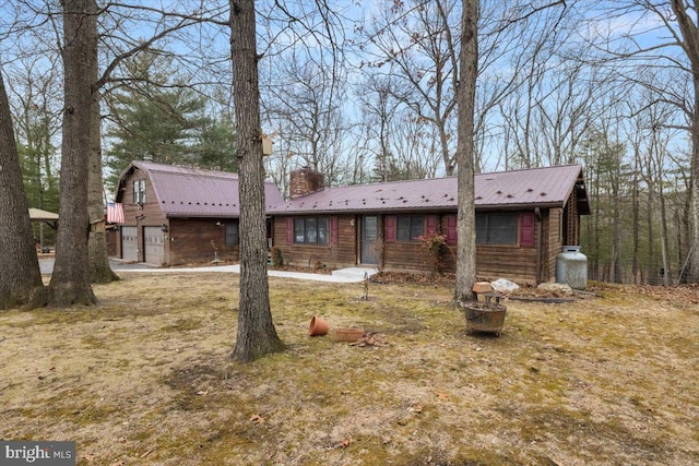 view of front of home featuring a chimney, a fire pit, metal roof, and a gambrel roof