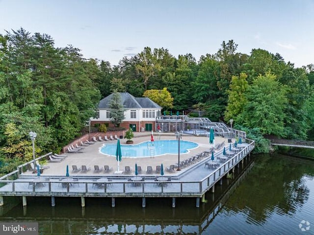 rear view of house with a water view and a community pool