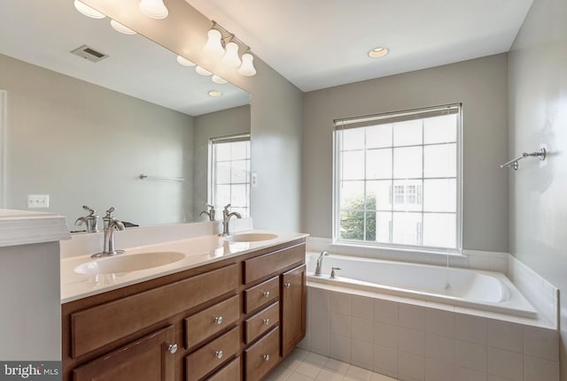 full bath featuring visible vents, a sink, a garden tub, and double vanity