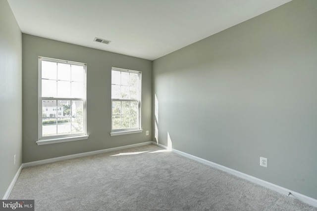 empty room featuring baseboards, visible vents, and light colored carpet