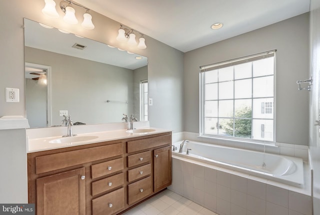 bathroom with double vanity, a garden tub, visible vents, and a sink