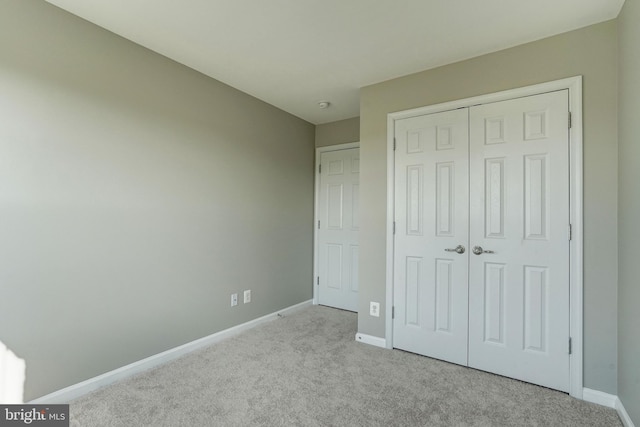 unfurnished bedroom featuring light carpet, a closet, and baseboards