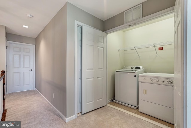 washroom featuring washing machine and clothes dryer, visible vents, light carpet, laundry area, and baseboards