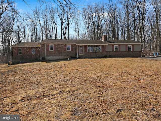 ranch-style home featuring brick siding, a chimney, and a front lawn