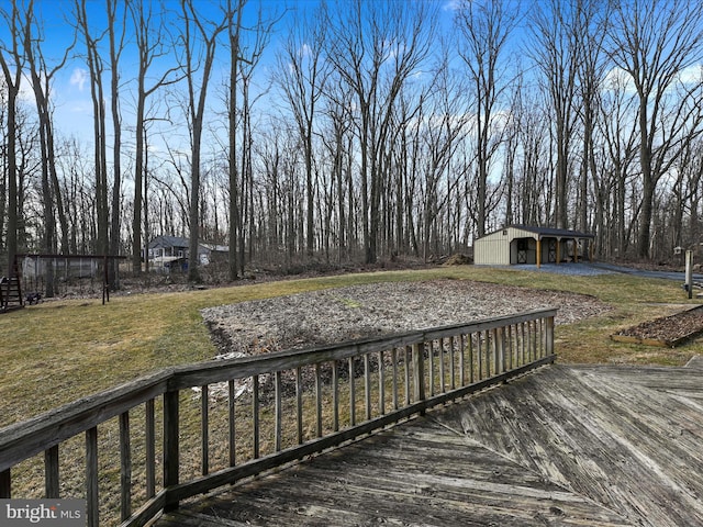 wooden terrace featuring a lawn and an outbuilding