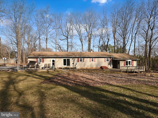 back of property with a lawn, a deck, and a patio