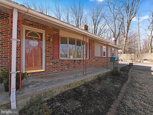 doorway to property featuring brick siding and a chimney