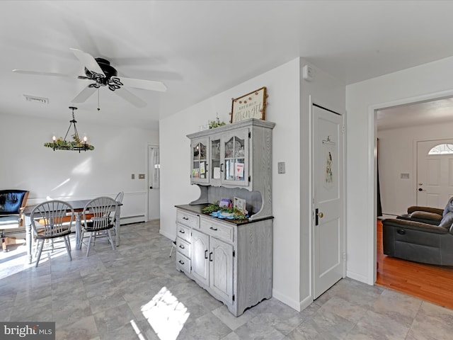 kitchen featuring visible vents, baseboards, dark countertops, a baseboard heating unit, and ceiling fan with notable chandelier