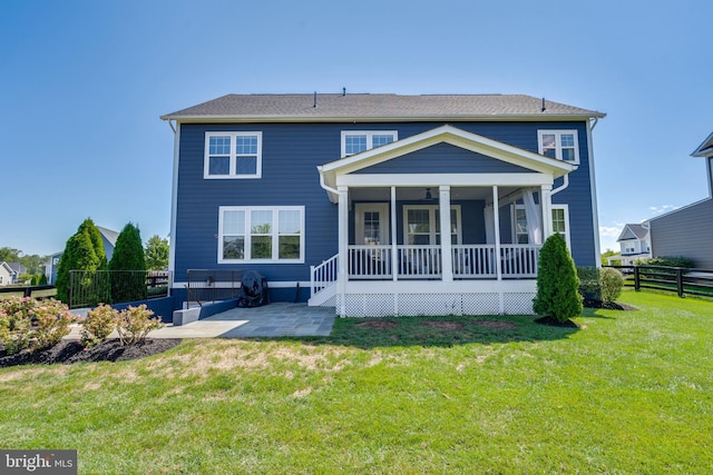 rear view of property with covered porch, a yard, a patio, and fence