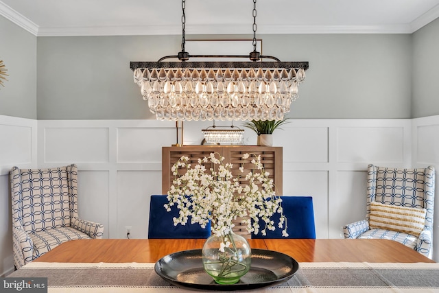 dining space with crown molding, wainscoting, and a decorative wall