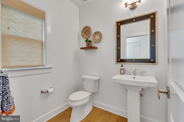 bathroom featuring toilet, baseboards, and wood finished floors