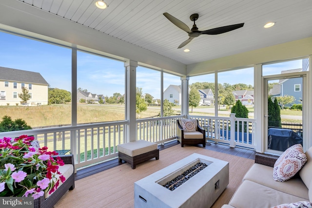 sunroom with a ceiling fan, wooden ceiling, a residential view, and a healthy amount of sunlight