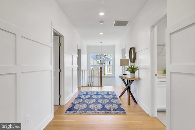 hall with recessed lighting, light wood-type flooring, visible vents, and a notable chandelier