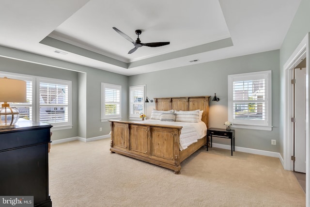 bedroom with light carpet, a raised ceiling, and visible vents