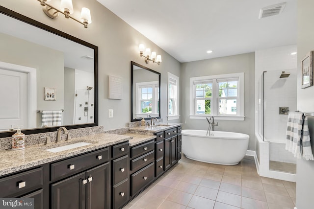 full bath featuring double vanity, a stall shower, visible vents, tile patterned floors, and a sink