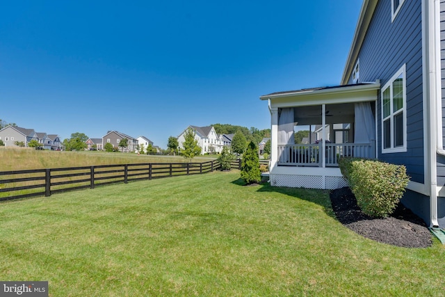 view of yard with a residential view, a sunroom, and a fenced backyard