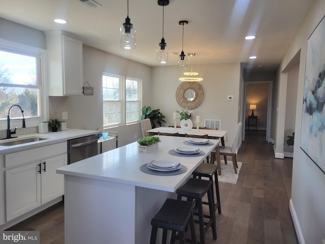 kitchen with dishwasher, a sink, a center island, and white cabinets