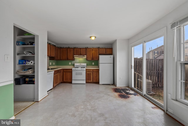 kitchen featuring light countertops, white appliances, brown cabinetry, and a sink