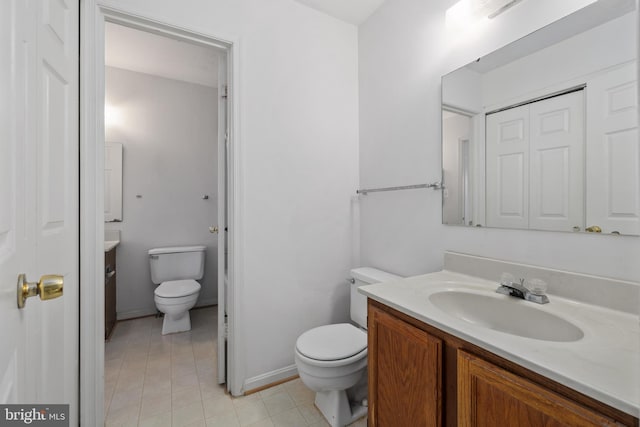 bathroom featuring toilet, tile patterned floors, baseboards, and vanity