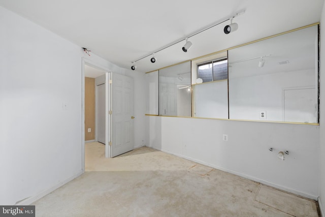 carpeted empty room featuring baseboards and track lighting