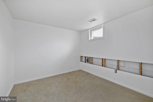 unfurnished room with carpet, visible vents, and baseboards