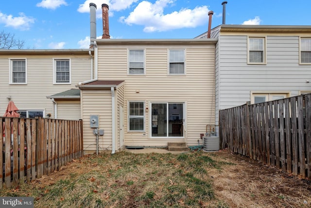 rear view of property with a fenced backyard and central AC