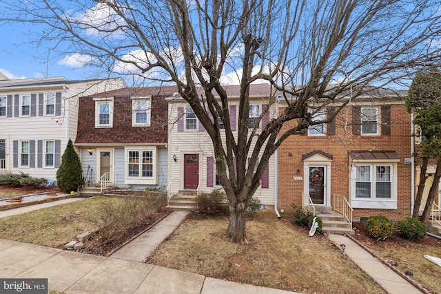 townhome / multi-family property featuring brick siding, a gambrel roof, and roof with shingles