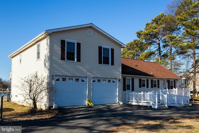 view of front facade featuring aphalt driveway, a garage, and a wooden deck