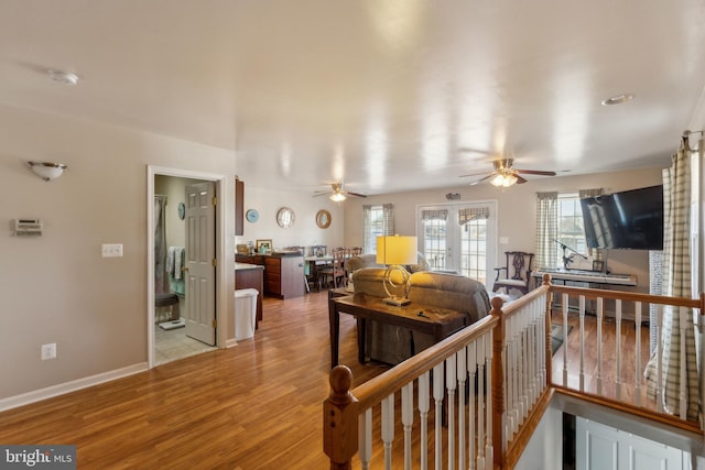 hall featuring baseboards, an upstairs landing, wood finished floors, and french doors