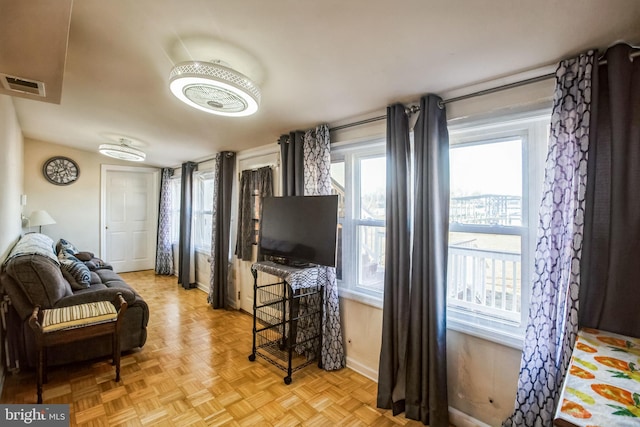 living area with a wealth of natural light, visible vents, and baseboards