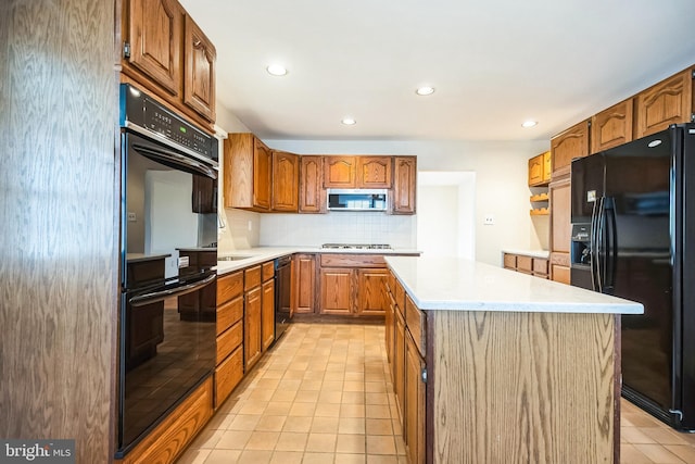 kitchen with brown cabinetry, decorative backsplash, a center island, light countertops, and black appliances