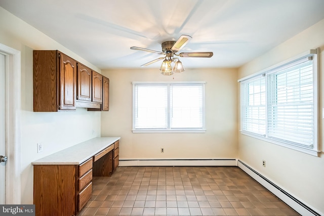 interior space featuring light countertops, a baseboard radiator, built in study area, and a ceiling fan