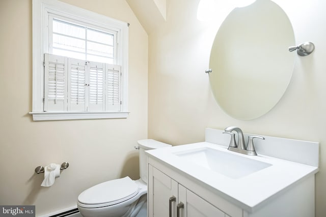 half bath with a baseboard radiator, vanity, and toilet