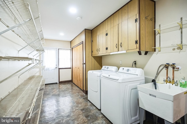 clothes washing area featuring washer and clothes dryer, a sink, and cabinet space