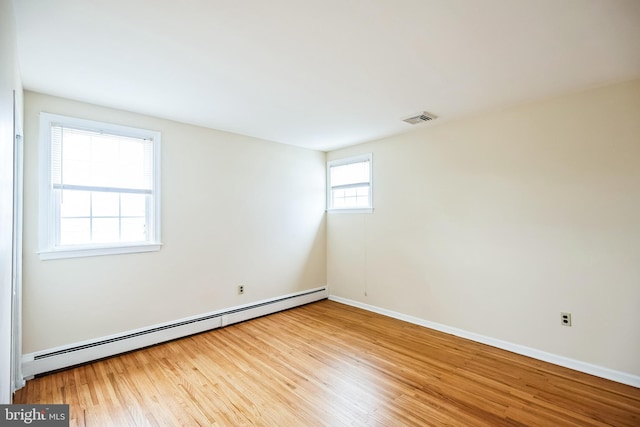 spare room featuring baseboards, a baseboard radiator, visible vents, and wood finished floors