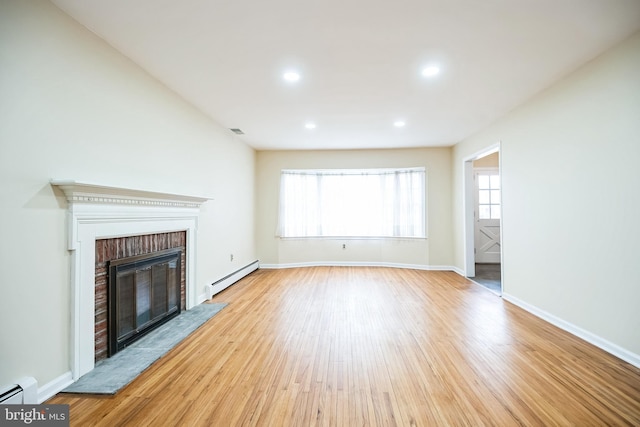 unfurnished living room featuring a baseboard radiator, a baseboard heating unit, a brick fireplace, wood finished floors, and baseboards