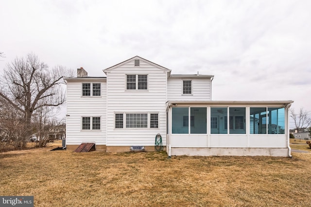 back of property featuring a sunroom, a yard, and a chimney