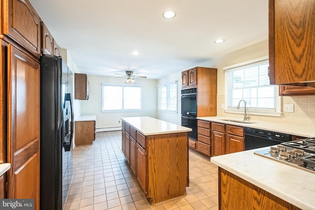 kitchen with a kitchen island, a sink, baseboard heating, backsplash, and black appliances